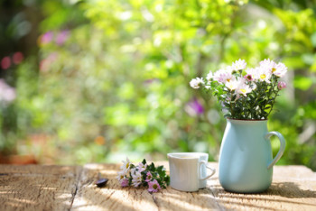 Flowers with vintage pot and heart shaped cup on wooden table